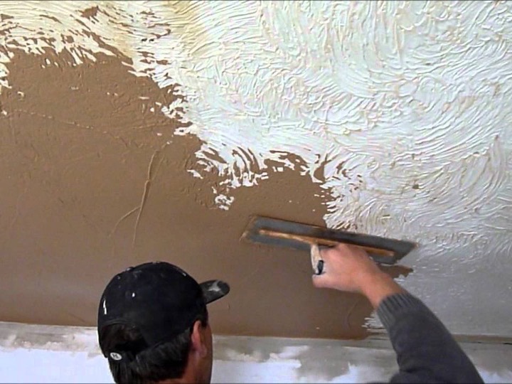 Plasterer skimming over a swirled Artex ceiling