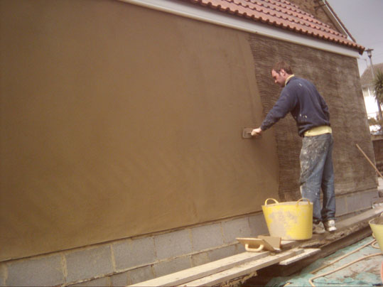 Plasterer rendering the outside wall of a house